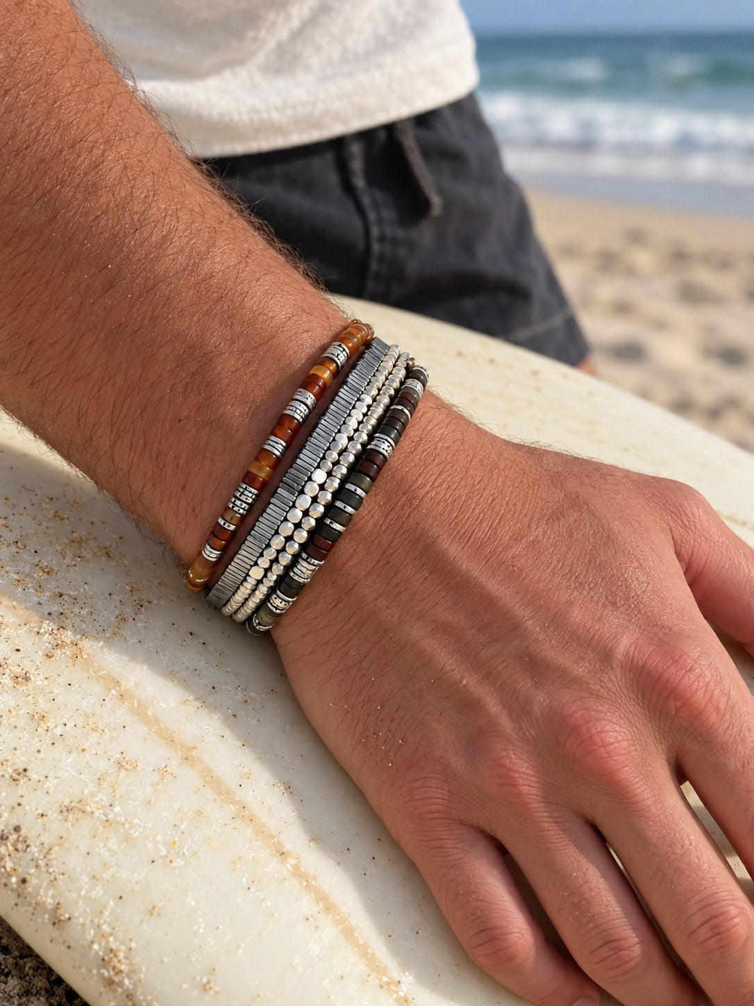 The Carnelian Set on the wrist, on a surfboard