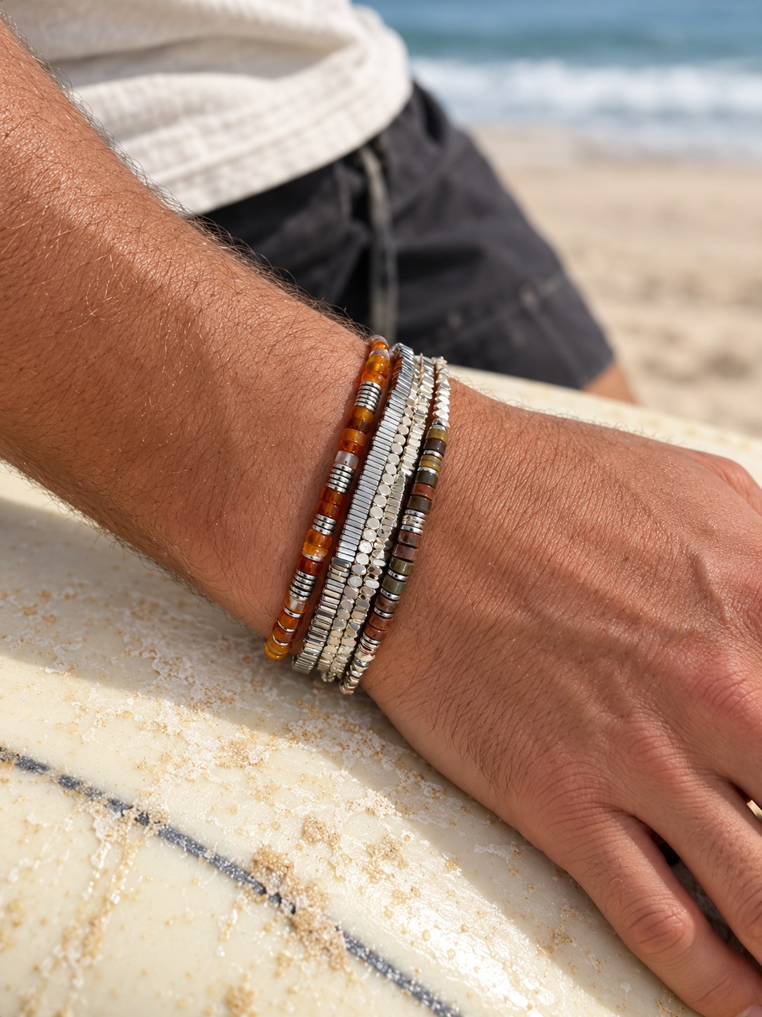 The Carnelian Set on the wrist, on a surfboard